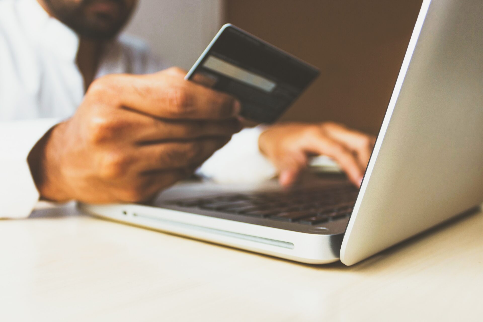 Photo of man holding our credit card while looking at a laptop computer.